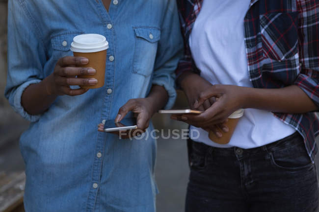 Средняя часть близнецов братьев и сестер с помощью мобильного телефона во время прогулки по тротуару — стоковое фото