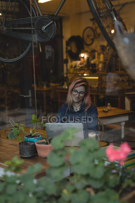 Mujer joven usando un portátil en la cafetería - foto de stock