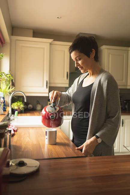 Беременная женщина готовит кофе на кухне дома — стоковое фото