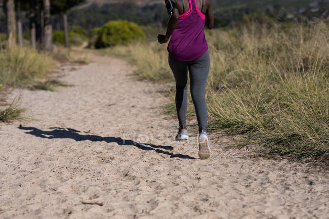 Вид ззаду спортсменки, що біжить у лісі — стокове фото