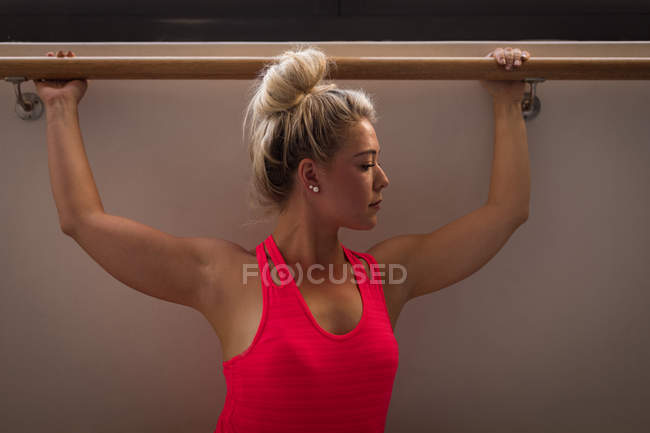 Mujer realizando ejercicio de barra en gimnasio - foto de stock