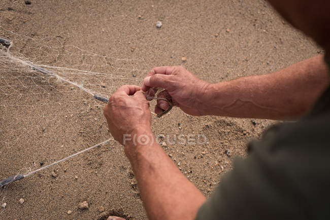 Средняя часть рыбака держит рыболовные сети на пляже — стоковое фото