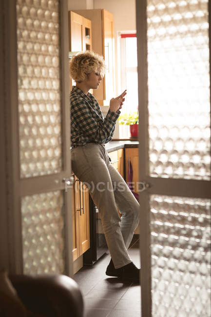 Mujer joven usando el teléfono móvil en casa - foto de stock