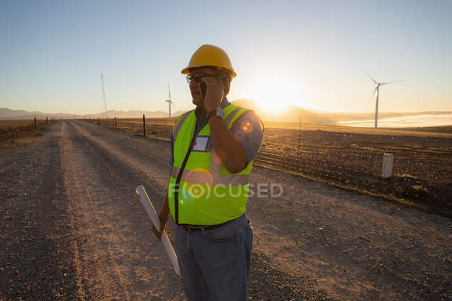 Інженер розмовляє на мобільному телефоні на вітроелектростанції — стокове фото