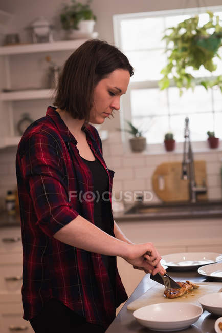 Женщина с мясом на кухне дома — стоковое фото