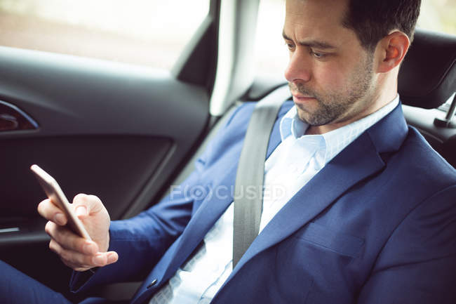 Uomo d'affari intelligente che utilizza il telefono cellulare in un'auto — Foto stock