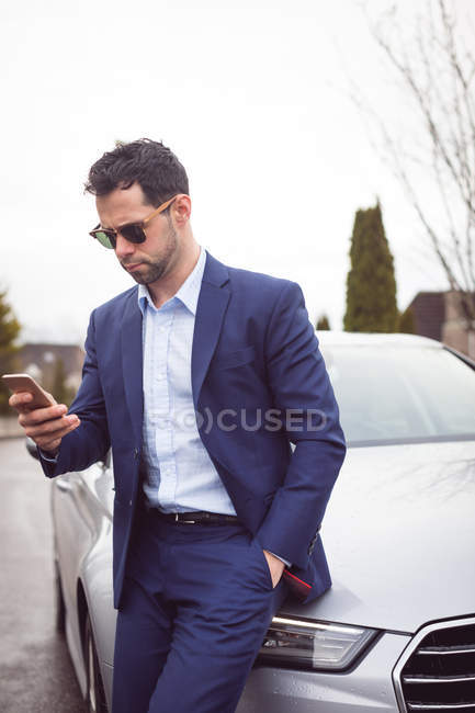 Schlauer Geschäftsmann benutzt Handy in der Nähe eines Autos — Stockfoto