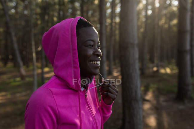 Nahaufnahme einer Athletin in Kapuzenjacke, die im Wald lächelt — Stockfoto