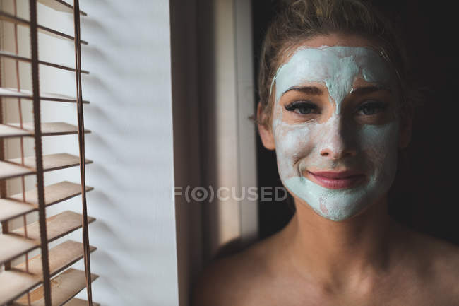 Женщина с кремом для лица в ванной комнате дома — стоковое фото