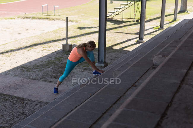Une jeune athlète féminine s'échauffe sur un site sportif — Photo de stock