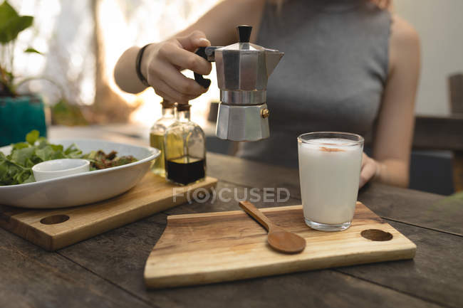 Young woman pouring coffee from a coffee kettle — Stock Photo