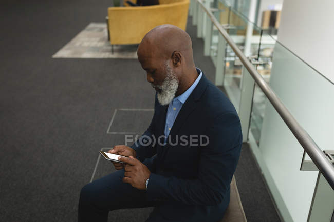 Бизнесмен с помощью мобильного телефона в офисном коридоре — стоковое фото