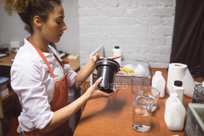 Fotógrafo feminino limpando uma tampa da lente com líquido no estúdio de fotografia — Fotografia de Stock