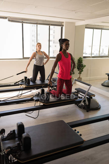 Dos mujeres haciendo ejercicio en la máquina de estiramiento en el gimnasio - foto de stock