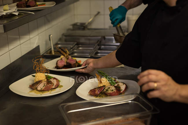 Средняя секция мужского шеф-повара, подающего еду в тарелке — стоковое фото