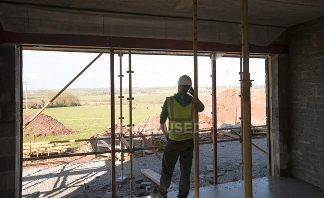 Rear view of engineer talking on the phone at the construction site — Stock Photo