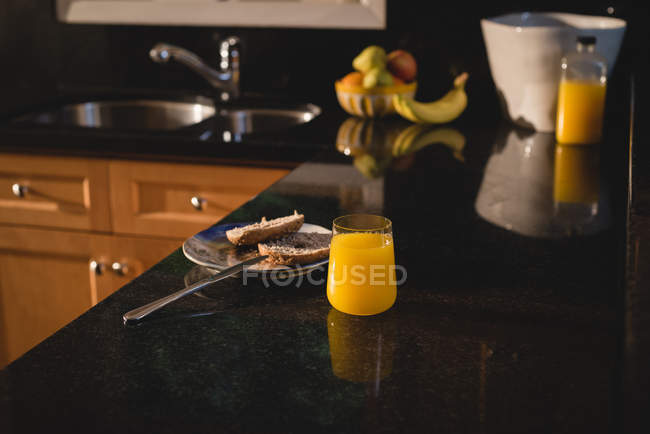 Fetta di pane e succo di frutta sul piano di lavoro della cucina a casa — Foto stock