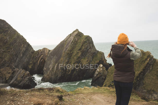 Jeune randonneuse regardant la mer avec des jumelles — Photo de stock