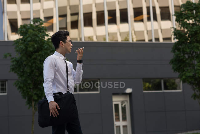 Молодой человек разговаривает по мобильному телефону во время прогулки по улице — стоковое фото