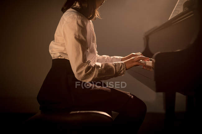 Средняя часть школьницы, играющей на фортепиано в музыкальной школе — стоковое фото