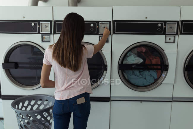 Junge Frau bedient Waschmaschine am Waschsalon — Stockfoto
