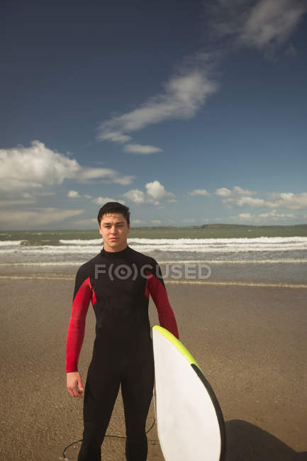 Ritratto di surfista con tavola da surf in piedi sulla spiaggia — Foto stock