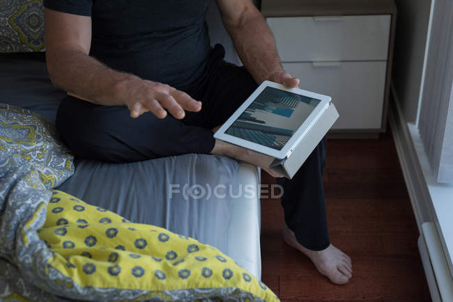 Seção média do homem usando tablet digital no quarto em casa — Fotografia de Stock