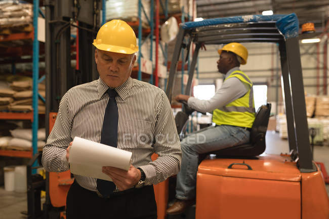 Male manager maintaining stock records in warehouse — Stock Photo