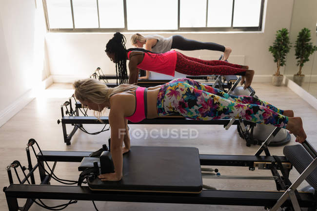 Grupo de mulheres se exercitando na máquina de alongamento no estúdio de fitness — Fotografia de Stock