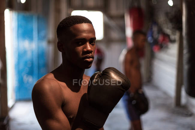 Jovem boxeador masculino praticando boxe no estúdio de fitness — Fotografia de Stock