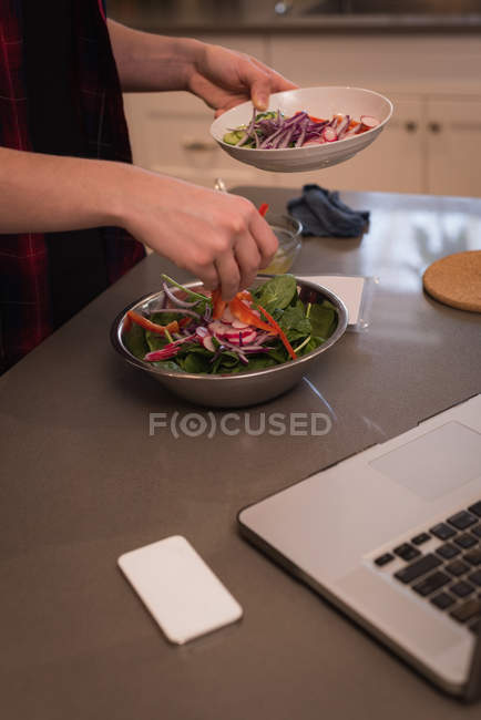Donna che prepara insalata in cucina a casa — Foto stock