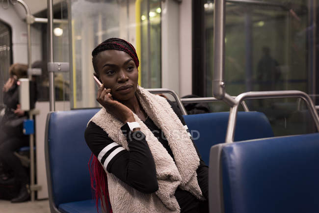 Молодая женщина разговаривает по мобильному телефону во время поездки на поезде — стоковое фото