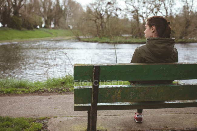 Hermosa mujer relajándose en el banco cerca del río - foto de stock
