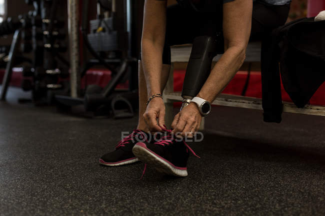 Низький розділ жінки з обмеженими можливостями зав'язування шнурків у спортзалі — стокове фото