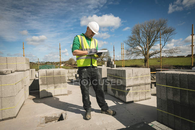Ingénieur écrivant sur le bloc-notes sur le chantier par une journée ensoleillée — Photo de stock
