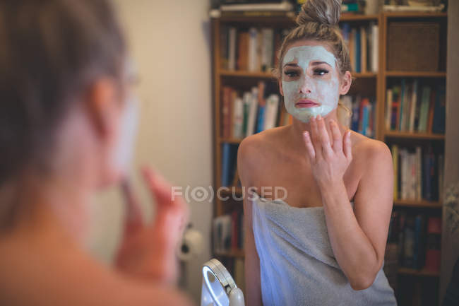Donna che applica la crema viso in bagno a casa — Foto stock