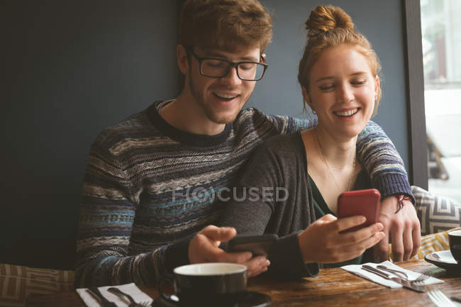 Romantisches Paar mit dem Handy im Restaurant — Stockfoto