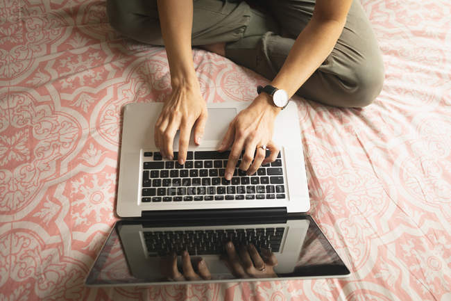 Вид з жінкою, використовуючи ноутбук на ліжку в спальні будинку — стокове фото