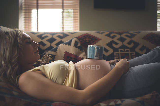 Mujer embarazada durmiendo en la sala de estar en casa - foto de stock