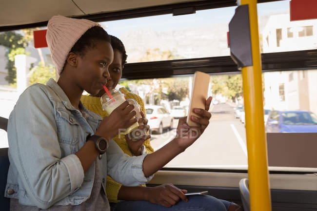 Twins siblings taking selfie with mobile phone in the bus — Stock Photo