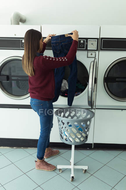 Молода жінка перевіряє свій одяг на пральні — стокове фото