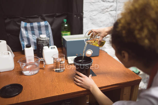 Fotografo femminile che versa una sostanza chimica sul coperchio dell'obiettivo nello studio fotografico — Foto stock