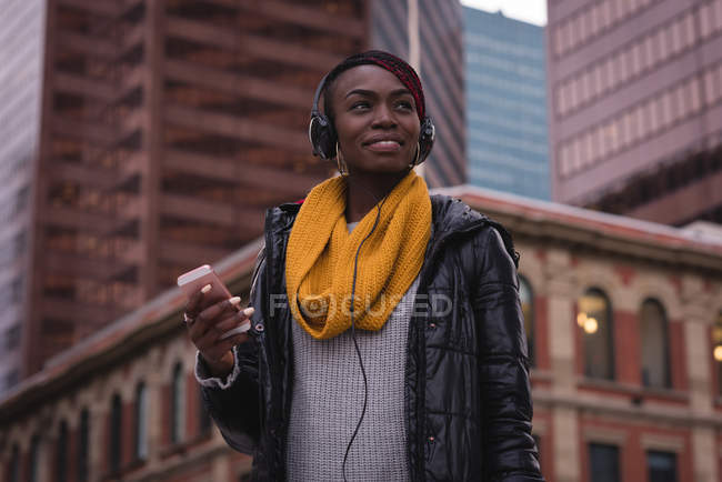 Mujer joven usando el teléfono móvil en la calle de la ciudad - foto de stock