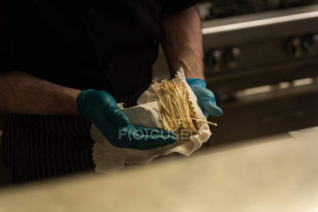 Mid section of male chef preparing noodles in kitchen — Stock Photo