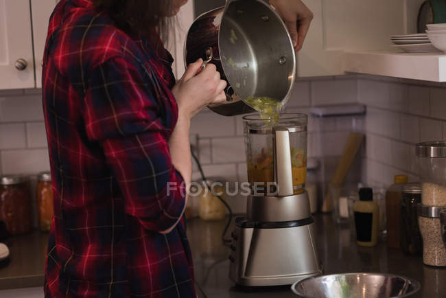 Femme utilisant broyeur mélangeur dans la cuisine à la maison — Photo de stock