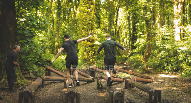 Homens aptos a treinar sobre o curso de obstáculos no campo de treinamento — Fotografia de Stock