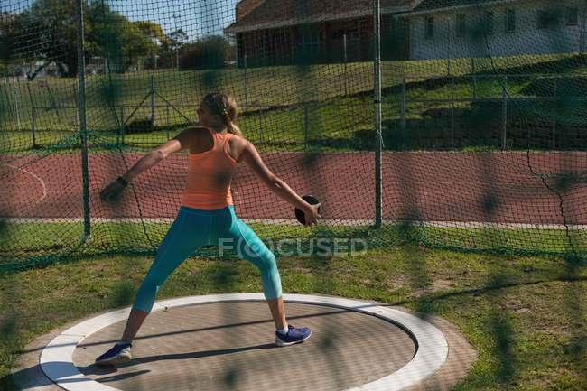 Atleta femenina practicando lanzamiento de disco en el recinto deportivo - foto de stock