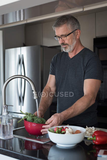 Mann wäscht Gemüse in Küche zu Hause — Stockfoto