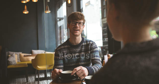 Lächelnder junger Mann spricht Frau im Café an — Stockfoto