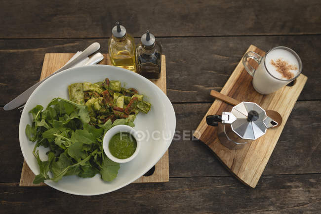 Salat und Kaffee auf einem Holzbrett in einem Café serviert — Stockfoto